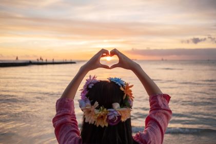 Woman making heart hands, sunset, Hawaii. 