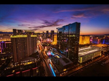 Aerial shot of Elara, a Hilton Grand Vacations Club lit up at nighttime with the busy Strip below in Las Vegas, Nevada.