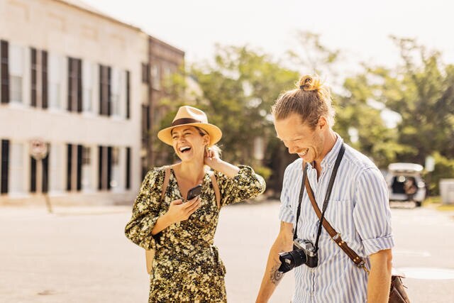 Couple with cameras and phones laughing while sightseeing, Charleston, South Carolina.