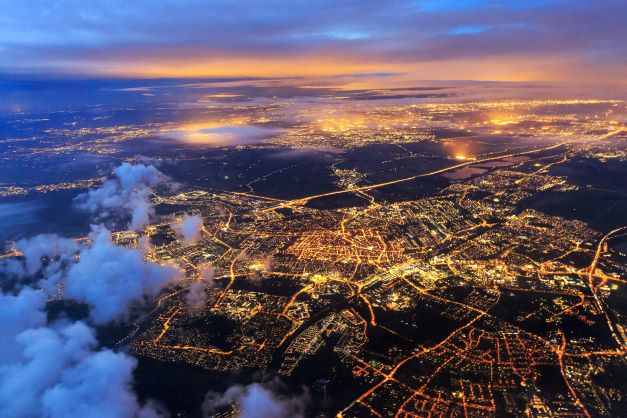 City lights glowing in night sky, airplane view.