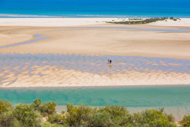 Beautiful aerial image, tourists walking along shoreline, Ria Formosa, the Algarve, Portugal. 