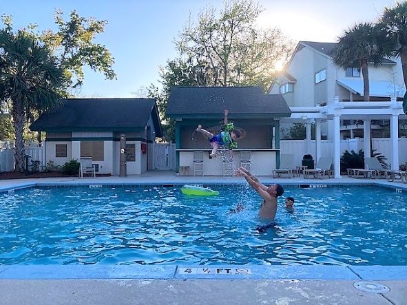 Hilton Grand Vacations Owner playing with young child in pool, Coral Sands Resort, Hilton Head Island, South Carolina.