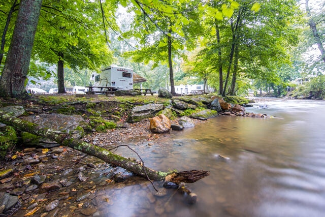 Peaceful stream with HGV Club Partner Perks Partner El Monte RV parked in the distance under verdent canopy, North Carolina.