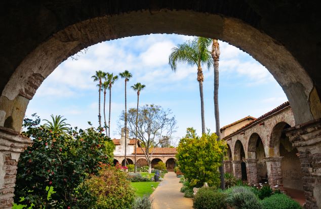 Beautiful image of lush coutyard taken through an arch way at Mission San Juan Capistrano, California. 
