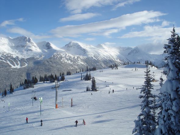 Picturesque snow-covered mountains dotted with downhill skillers, Whistler, Canada. 