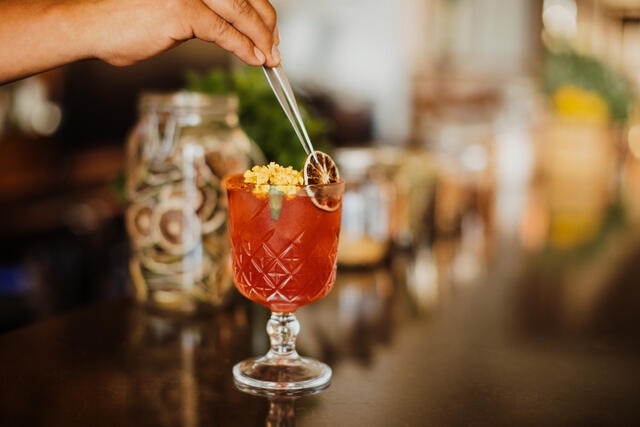 Close up, bartender placing garnish in craft cocktail, Los Cabos, Mexico. 