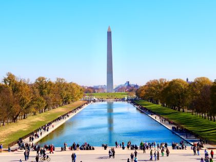 The Washington Monument and reflecting pool on a sunny day with tourists in Washington, D.C.