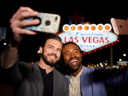 Two people take selfies by the famous "Welcome to Fabulous Las Vegas" sign